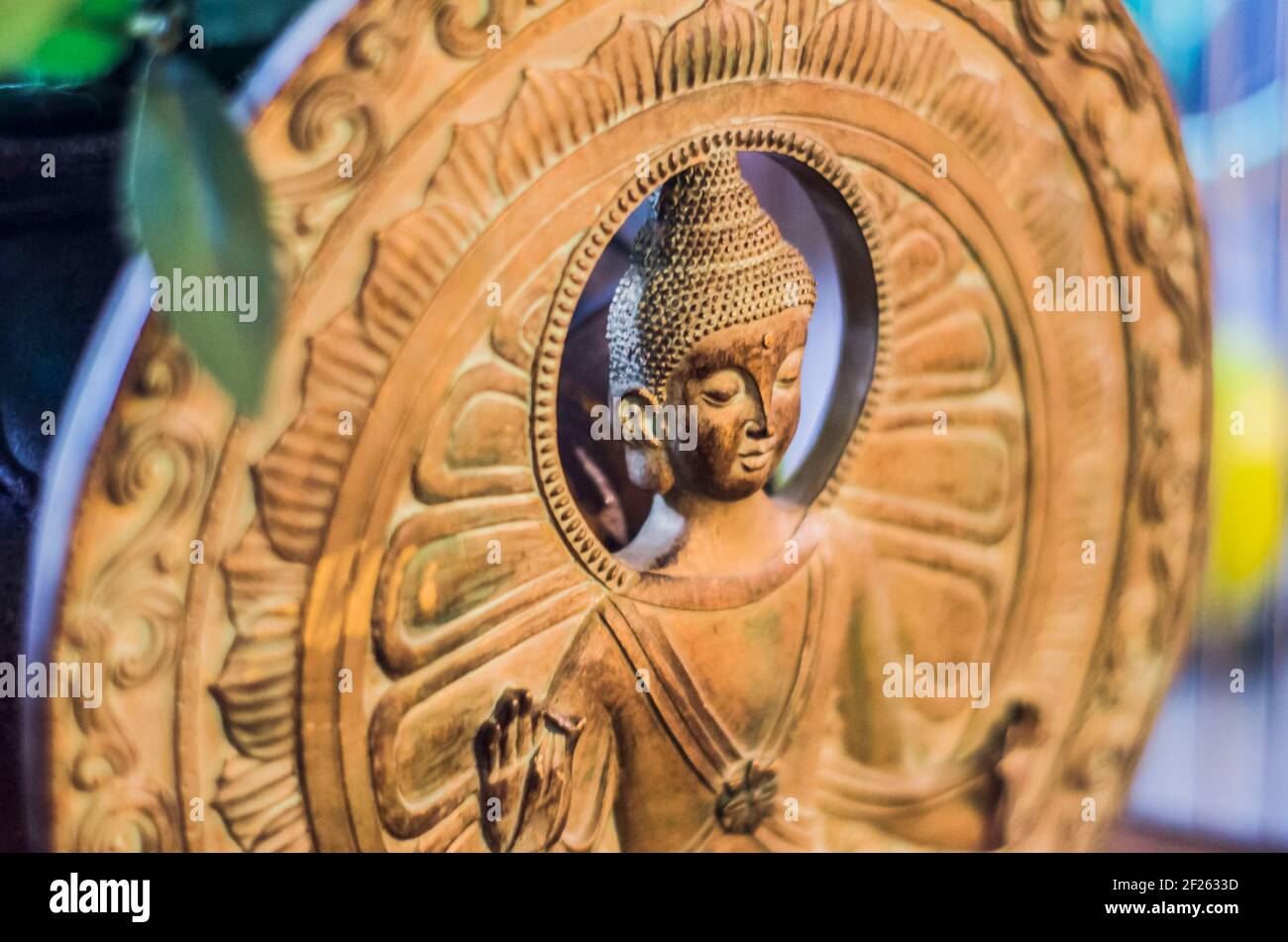 Statuina di Buddha su sfondo di cerchi di bronzo. Figurina sacrale all'interno. Foto Stock