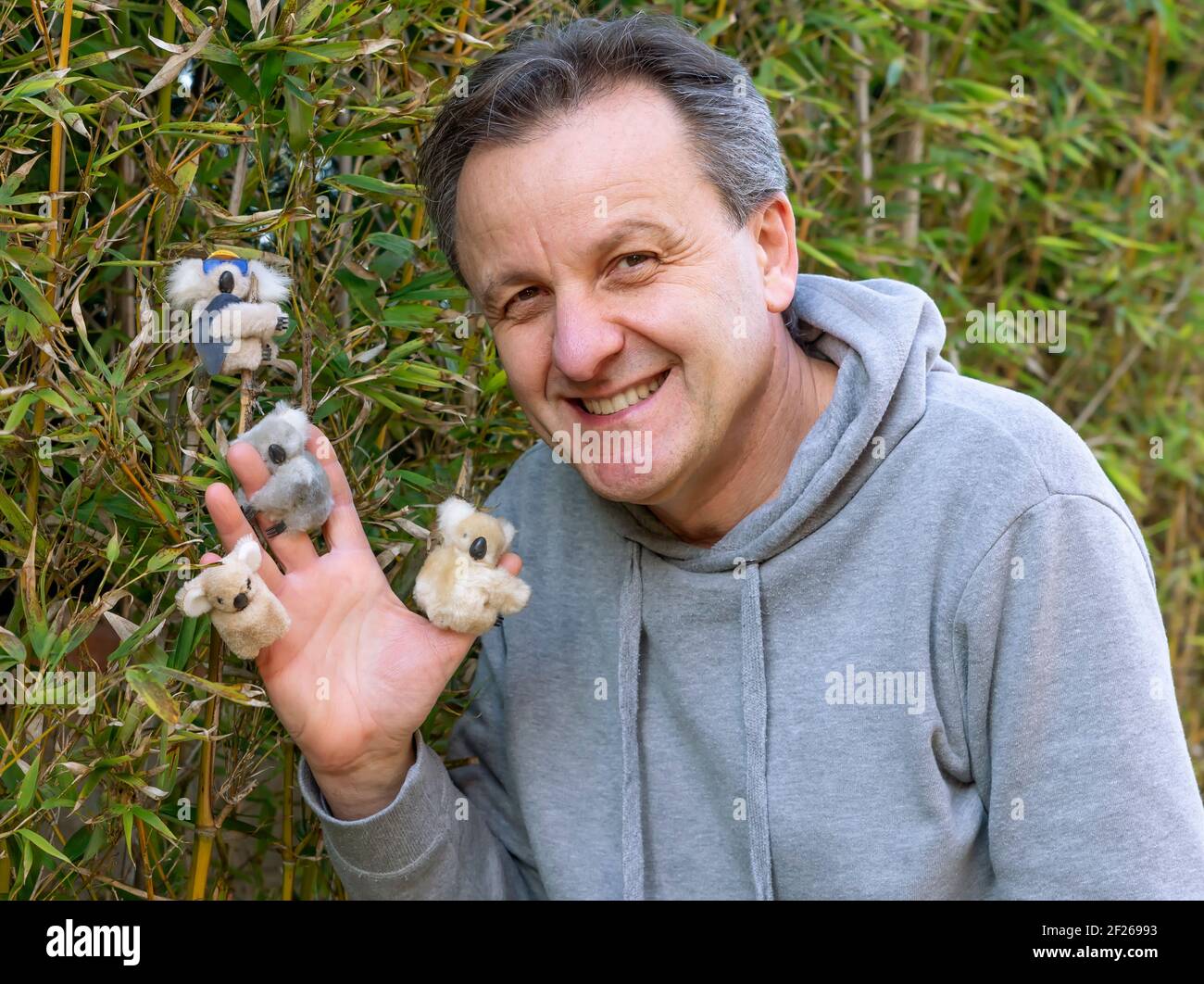 Un uomo di mezza età gioca con piccoli animali farciti a forma di koala Foto Stock
