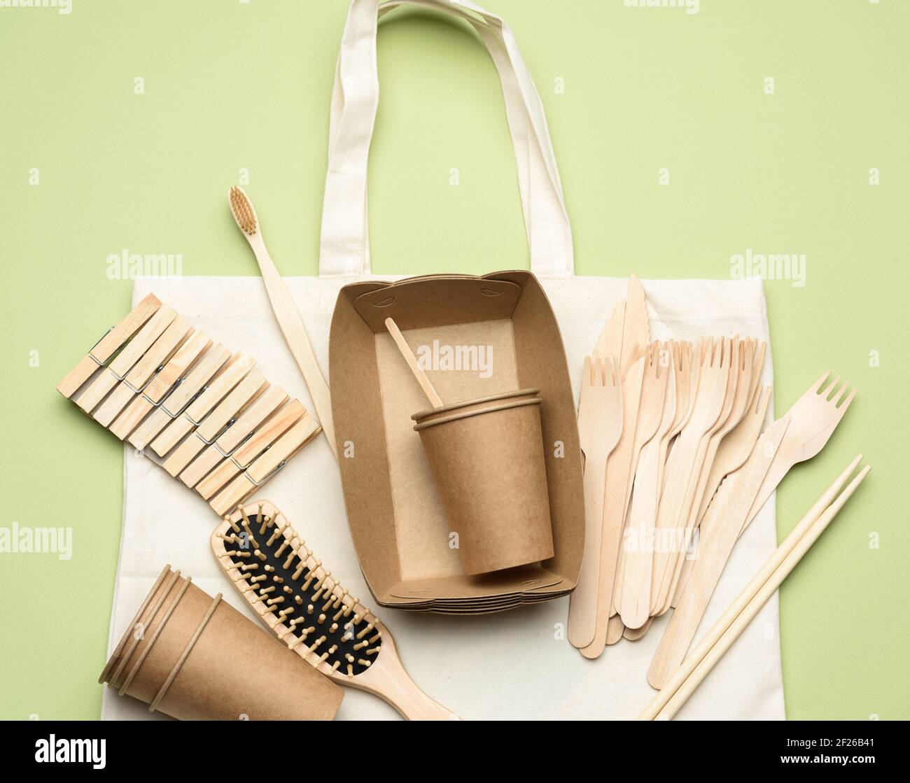 Borsa in tessuto bianco e stoviglie monouso di carta da artigianato marrone su sfondo verde Foto Stock