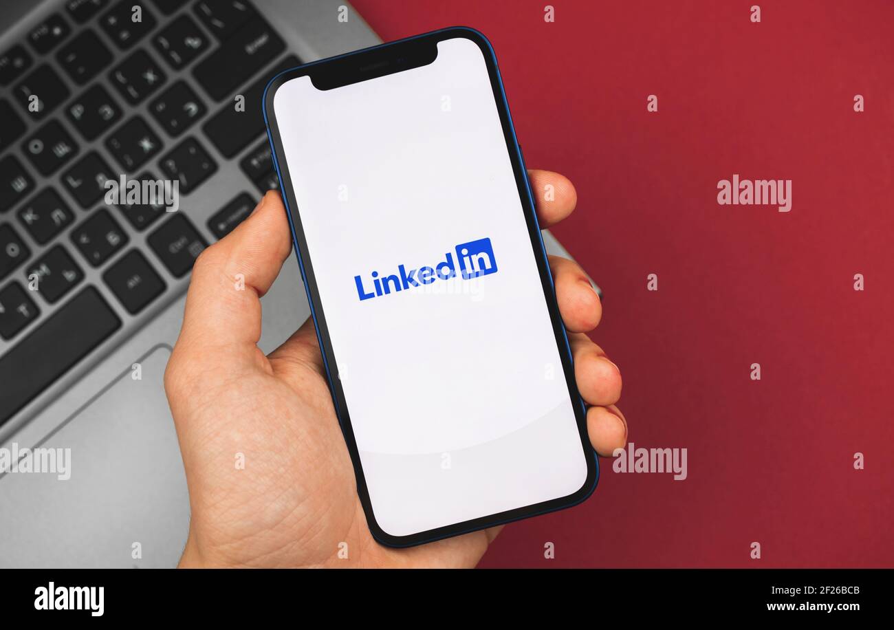 Kharkov, Ucraina - 9 marzo 2021: L'uomo possiede uno smartphone con l'app LinkedIn aperta, foto di sfondo aziendale Foto Stock