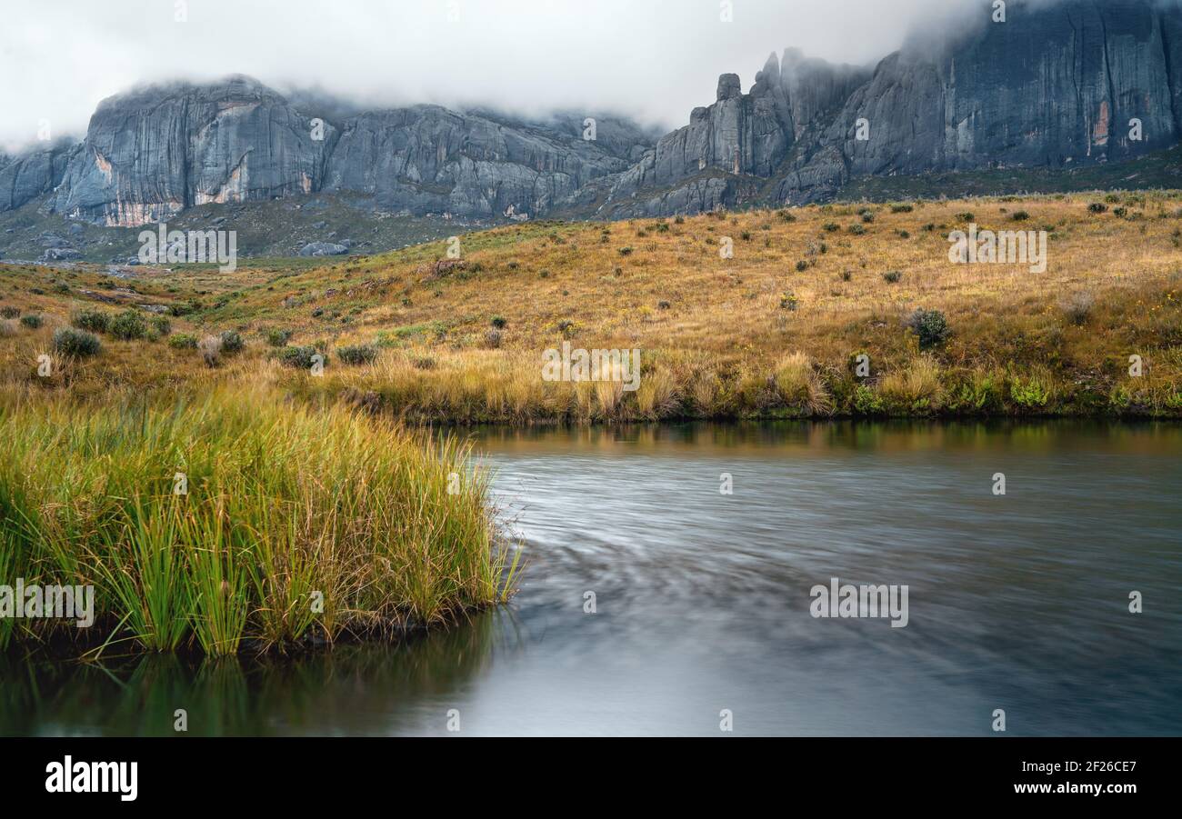 Andringitra Massiccio visto dal campo base durante il trekking a Pic Boby (la vetta più alta accessibile del Madagascar), piccolo fiume che scorre in primo piano Foto Stock