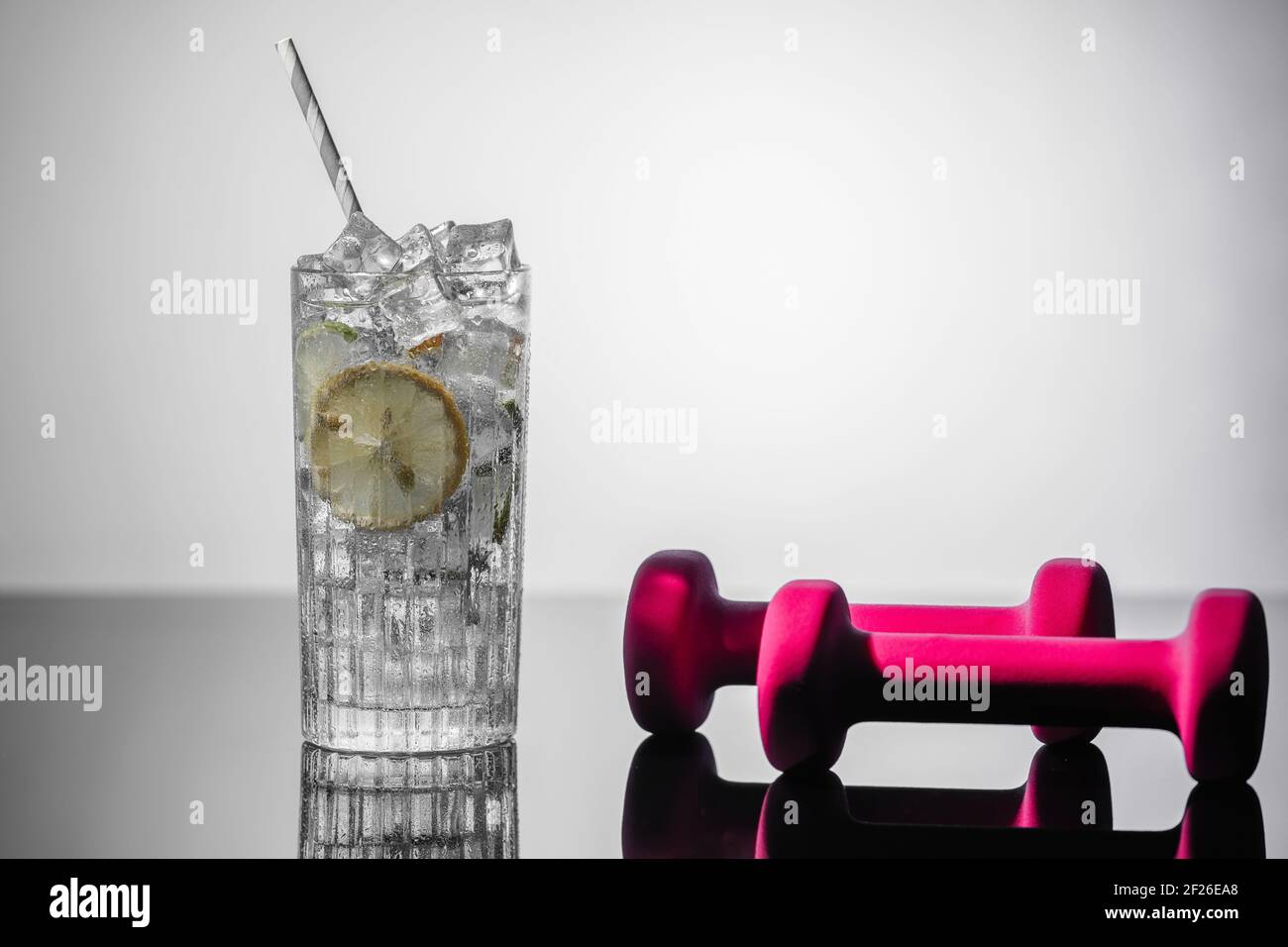 Un bicchiere d'acqua, lime, limone e manubri. Concetto di disintossicazione Foto Stock