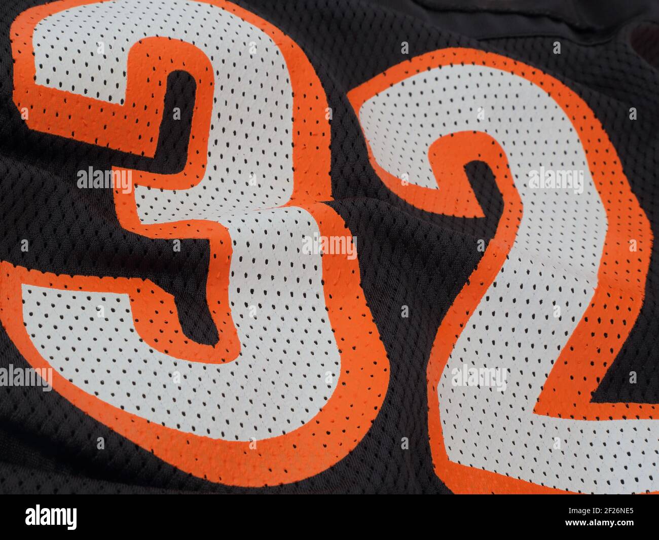 I numeri arancioni e bianchi mostrano da vicino 32 su una maglia sportiva in mesh nera. Foto Stock