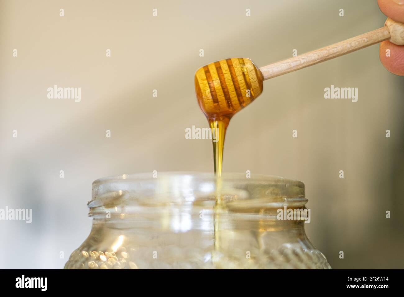 Miele gustoso crudo su un cucchiaia di legno chiuso, colazione sana ingredienti Foto Stock