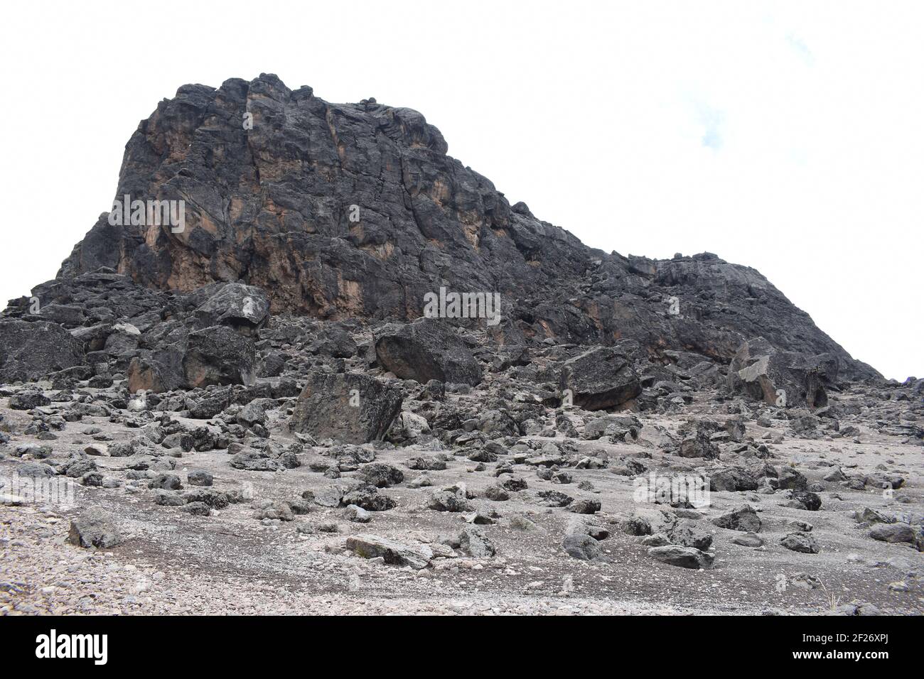 Vista della Torre di Lava con massi vulcanici sparsi di fronte all'interno della zona del deserto alpino sulle pendici del Monte Kilimanjaro. Foto Stock