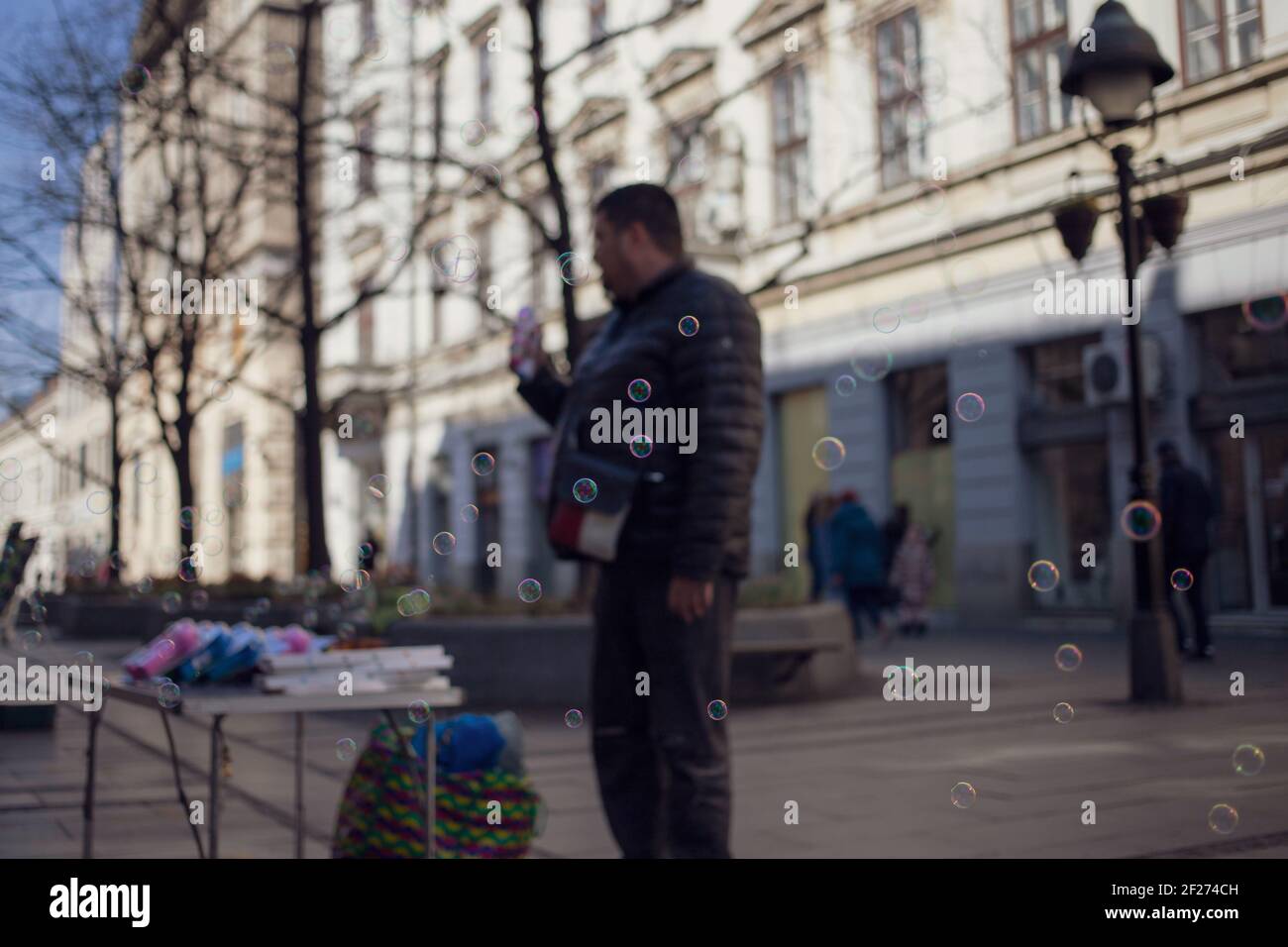 Fornitore di strada che dimostra un giocattolo per soffiatori di bolle Foto Stock