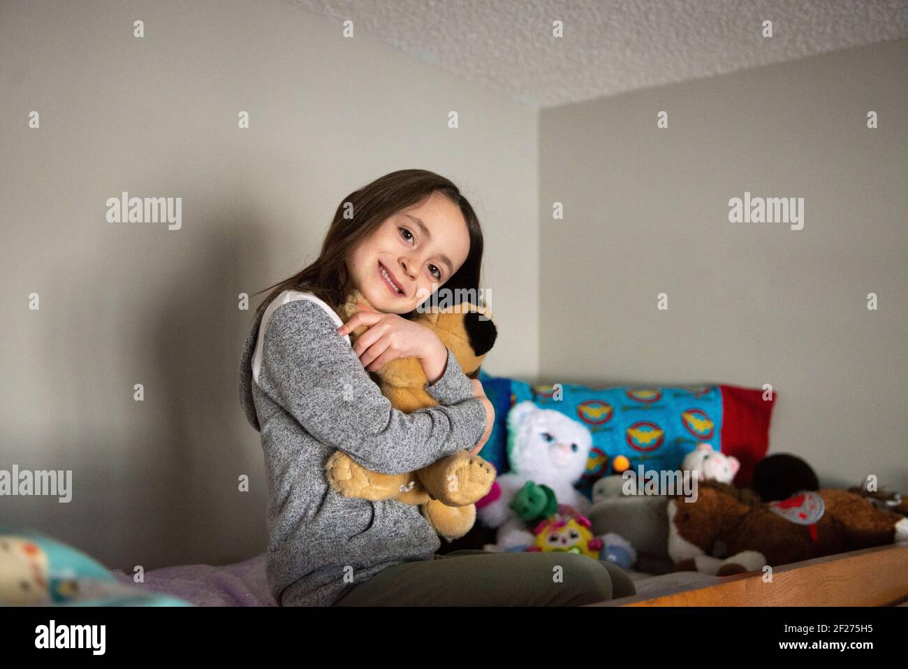 Bambina in cima a un letto a castello abbracciando un animale farcito. Foto Stock
