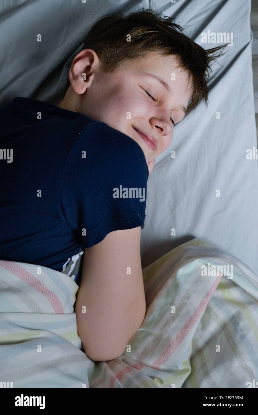 ragazzo sorridendo mentre dormiva nel letto Foto Stock