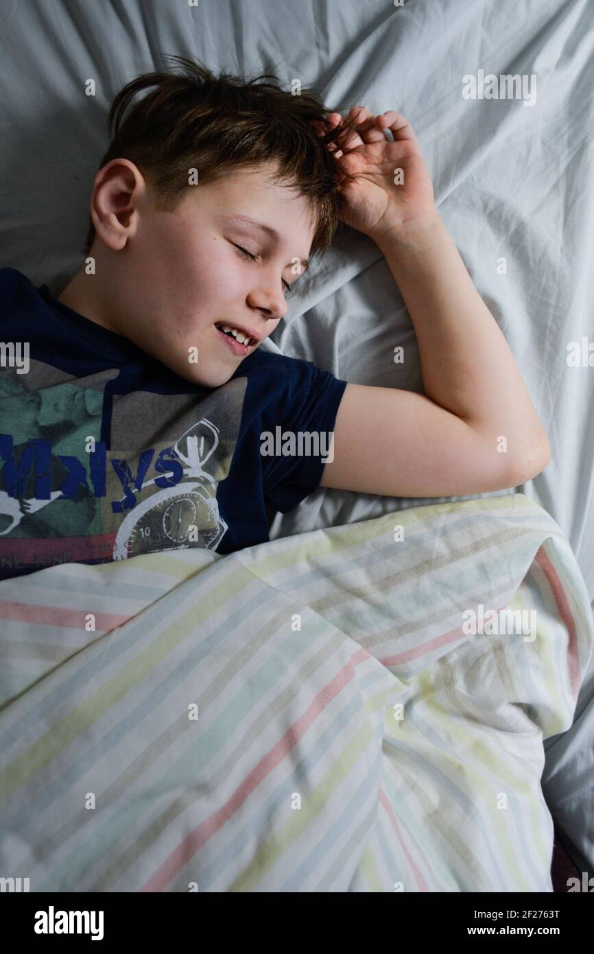 ragazzo che slitta sorridendo nel suo letto di mattina Foto Stock