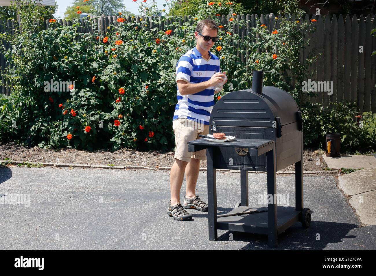 Uomo che inizia una grigliata in una giornata estiva soleggiata Foto Stock