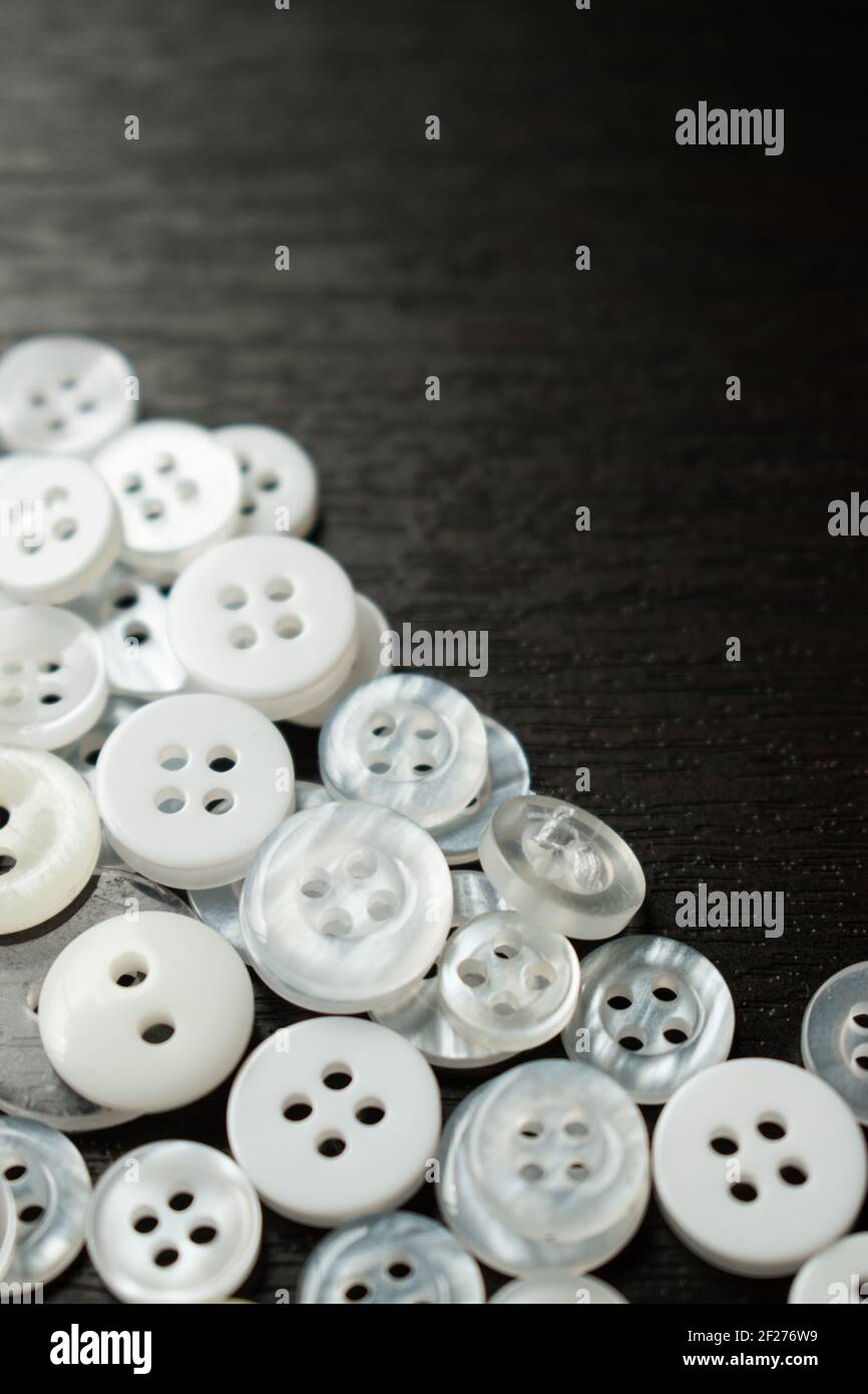 Alcuni bottoni bianchi su un tavolo di legno nero Foto stock - Alamy