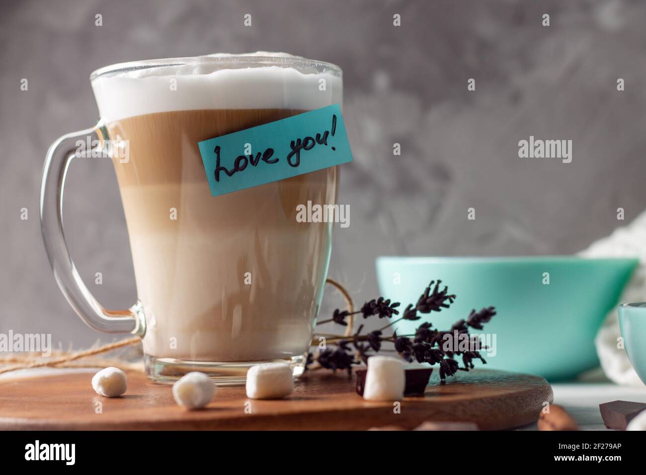 Tazza di caffè latte con adesivo Love You su vassoio di legno con recipiente turchese, su fondo grigio Foto Stock