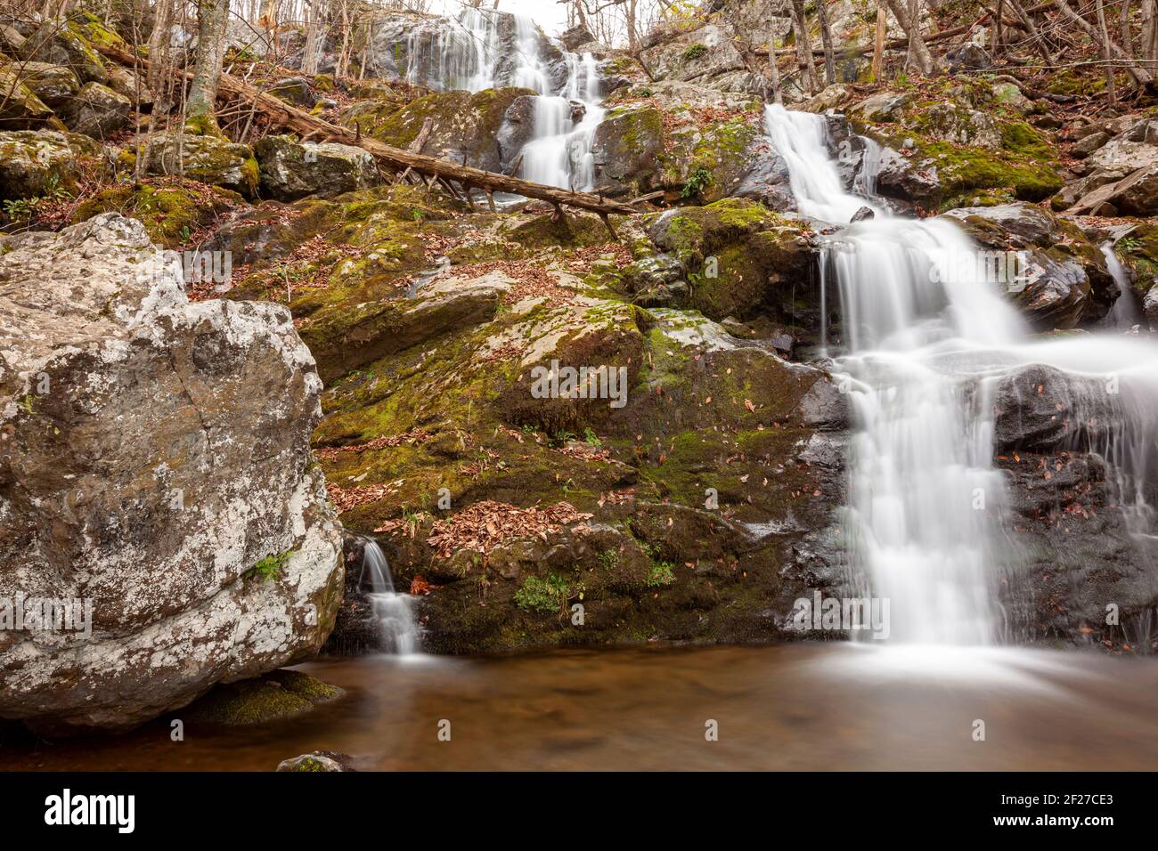 Immagine a lunga esposizione delle Dark Hallow Falls nel Parco Nazionale di Shenandoah in autunno. L'immagine presenta acqua a cascata che scende lungo la montagna coperta wi Foto Stock