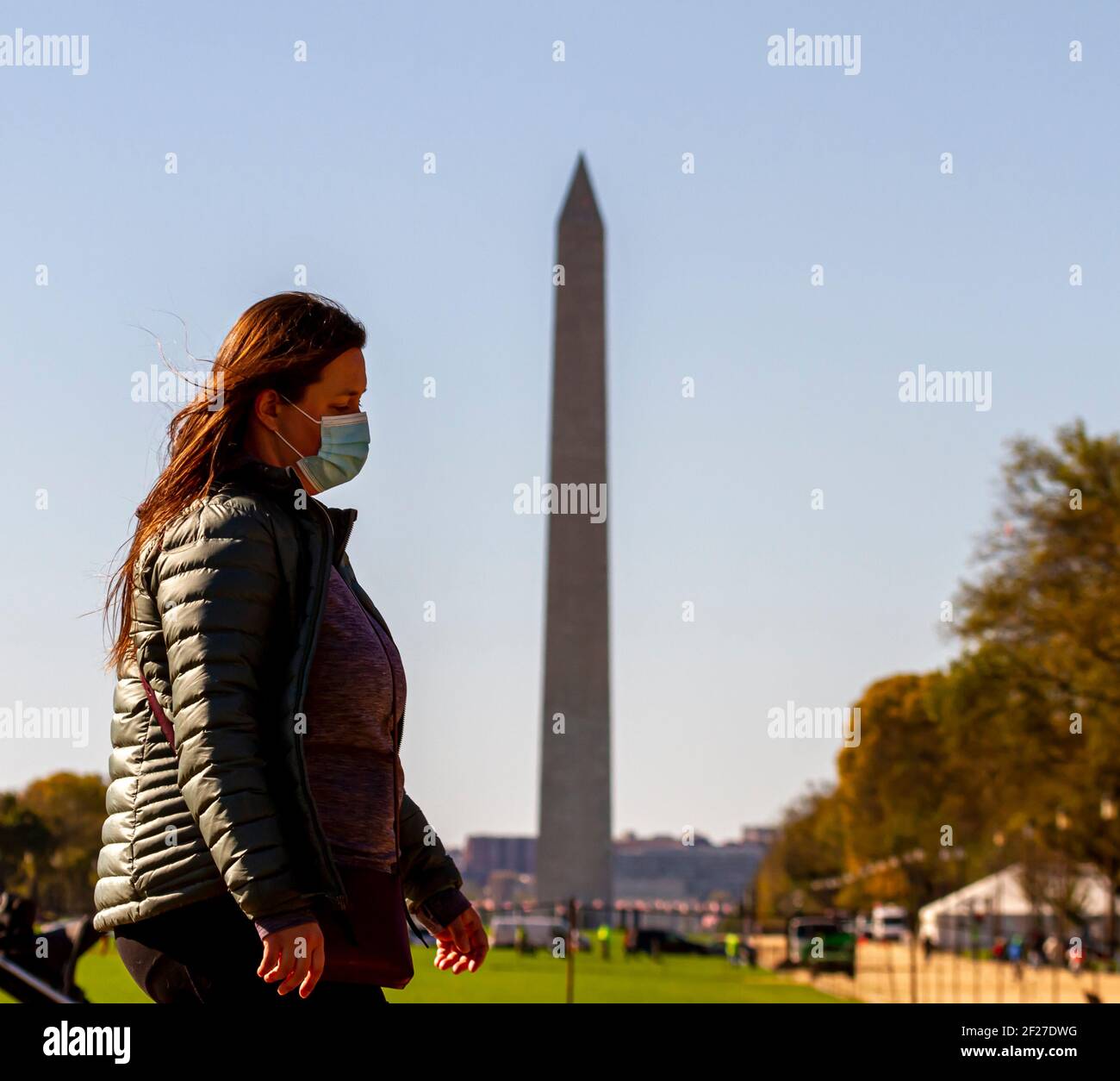 Washington DC, USA 11-02-2020: Una donna caucasica con i capelli marroni sta camminando nel National Mall indossando la maschera a causa della pandemia COVID-19. Washington Mo Foto Stock