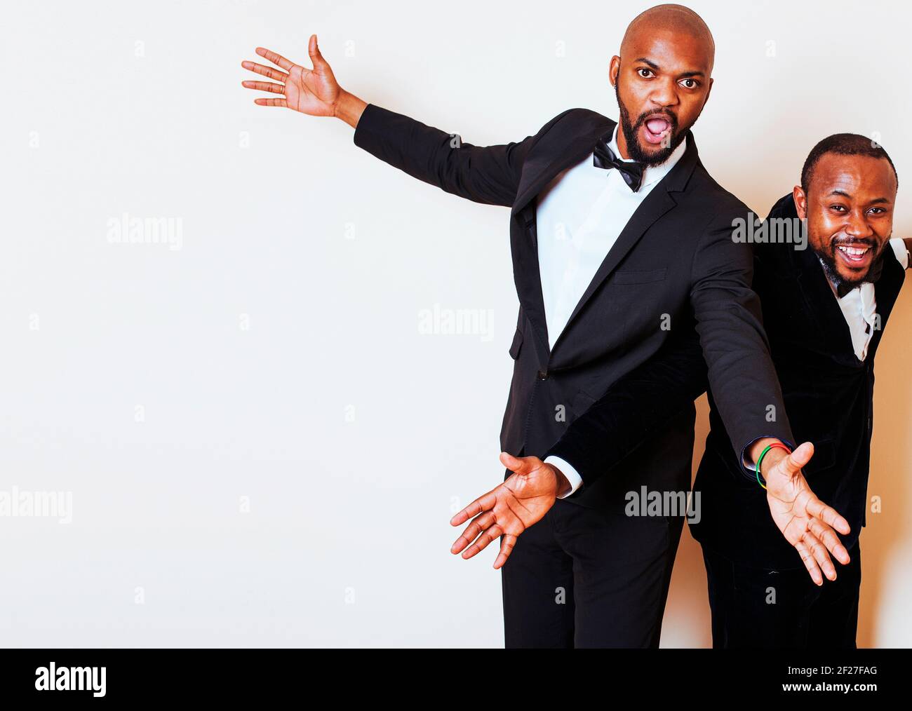 Due afro-american businessmen in nero si adatta ponendo emotivo, gesticolando, sorridente. Indossare bow-cravatte Foto Stock