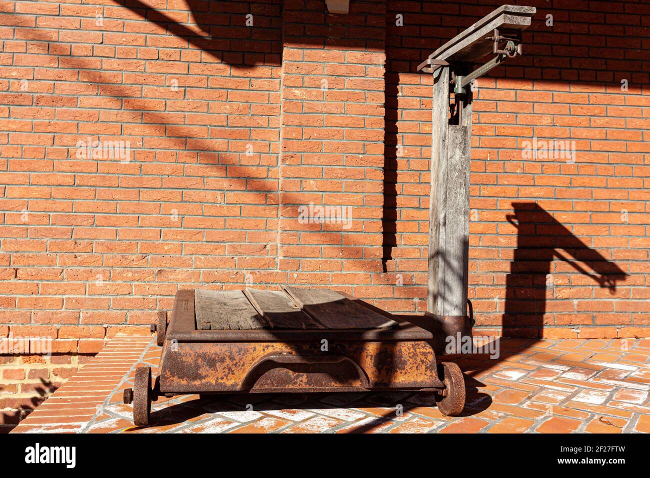 Una bilancia a piattaforma industriale vintage di dimensioni arrugginite con ruote in metallo e bilanciamento del fascio. Questo articolo antico è in mostra sulla piattaforma del 19 ° storico Foto Stock