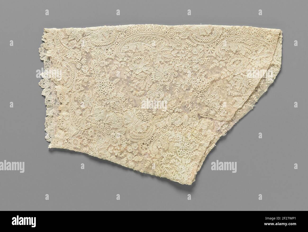 Mouw van een strook naaldkant met voluten en pioenrozen.manicotto di lato ago naturale: Bordo maglia Bruxelles. Modello rettangolare rastremato con lato inclinato, composto da parti diverse che vengono unite con un rivestimento rosa chiaro di tulle di macchine non lavorate. Il motivo a lacci ad ago di rami di fiori e C-voluten asimmetrico su un terreno fine con maglie monogirate: Un terreno laterale a maglia, cosparso di moi. Lavoro completo realizzato con punti di festone con sfumature dove il riempimento più denso è fatto con punti di polvere (una variante di punto di festone). Contorni in rilievo di fasci di fili diffusi (cordonnet) Foto Stock