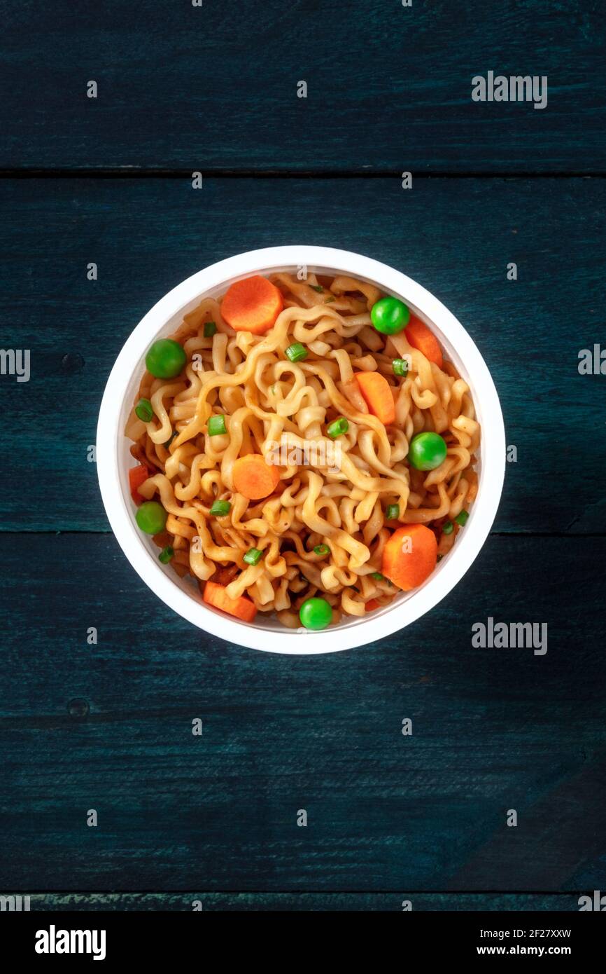 Coppa ramen. Spaghetti istantanei in una tazza di plastica, con top shot su sfondo di legno Foto Stock