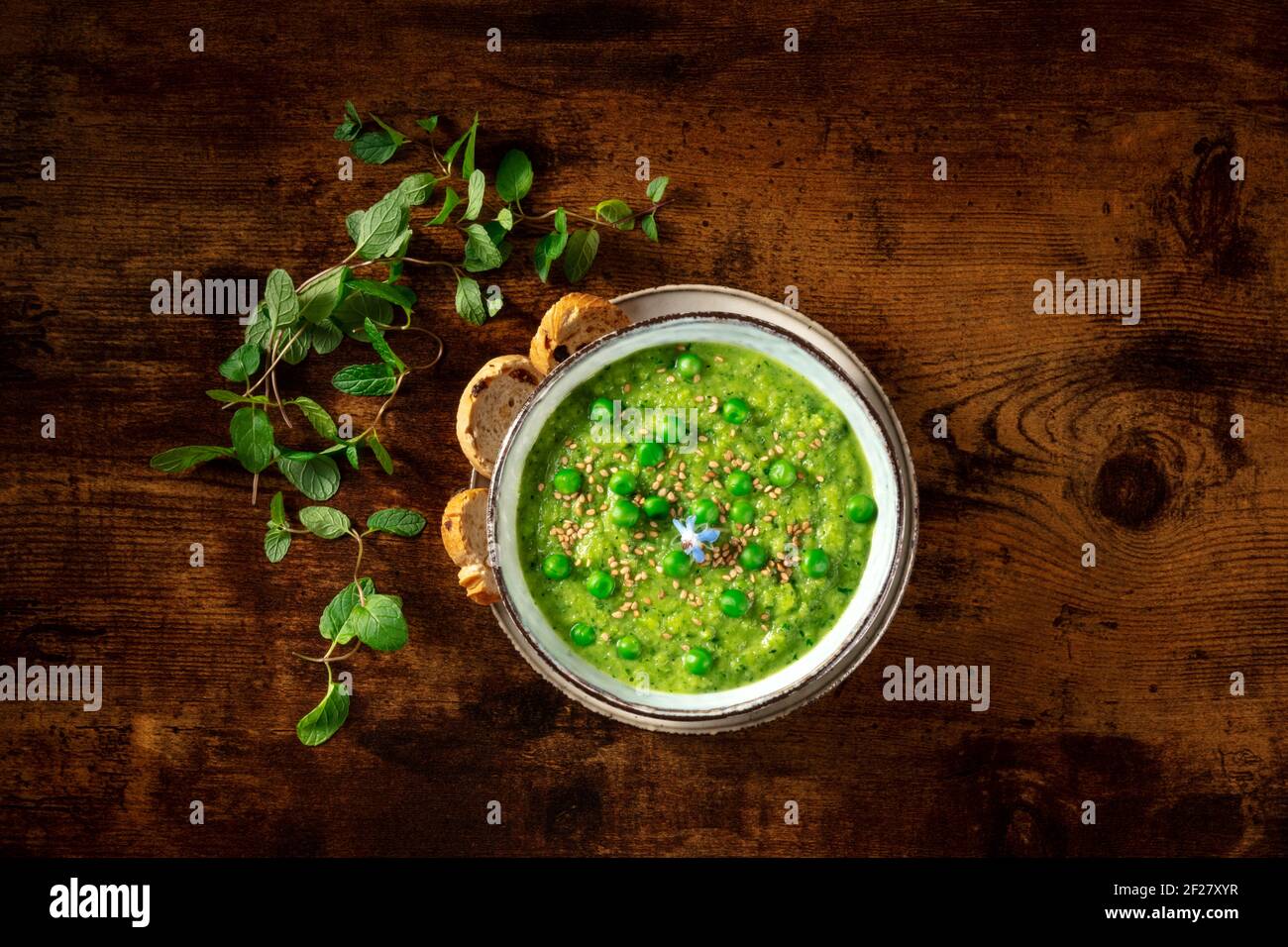 Zuppa di crema verde, sparata dall'alto su uno sfondo di legno rustico scuro Foto Stock
