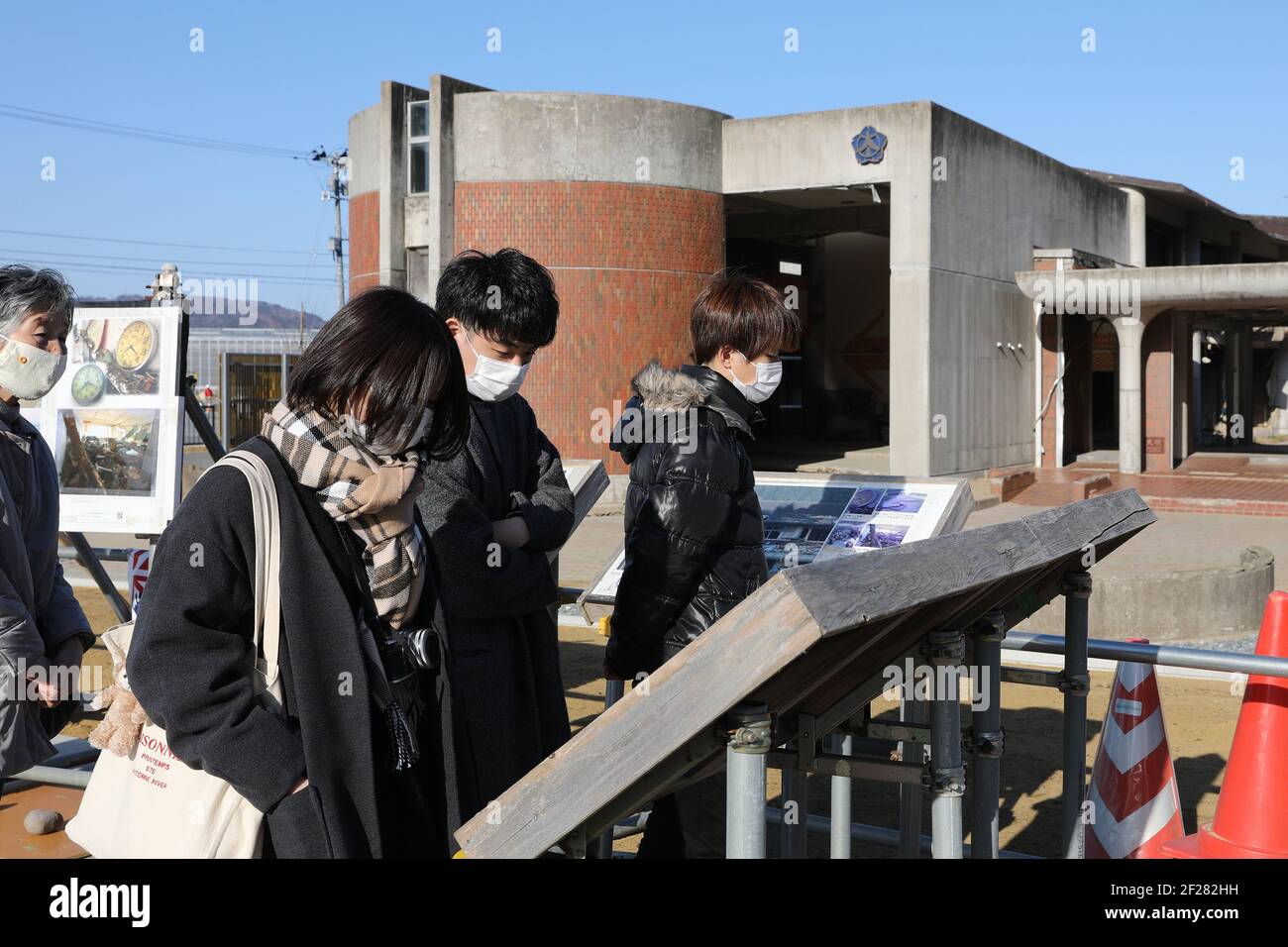 Ishinomaki, Giappone. 9 marzo 2021. I visitatori guardano le foto della scuola prima del disastro esposto alle rovine della scuola elementare di Okawa a Ishinomaki, Giappone, il 9 marzo 2021. Una scuola elementare pubblica nella prefettura di Miyagi ha perso più di 80 vite nello tsunami a seguito del terremoto del 2011 marzo nel Giappone nordorientale. Dieci anni dopo, le rovine dell'edificio scolastico raccontano ancora l'inimmaginabile tragedia della calamità. PER ANDARE CON 'Feature: 10 anni dopo, la scuola giapponese di tsunami-colpito ancora dice tragedia inimmaginabile' Credit: Du Xiaoyi/Xinhua/Alamy Live News Foto Stock