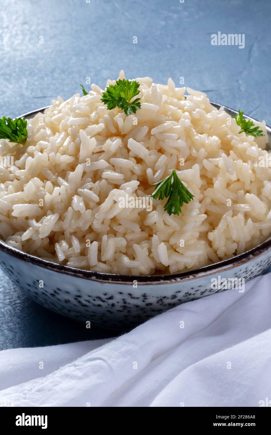 Riso bianco a grani lunghi da vicino su sfondo blu Foto Stock