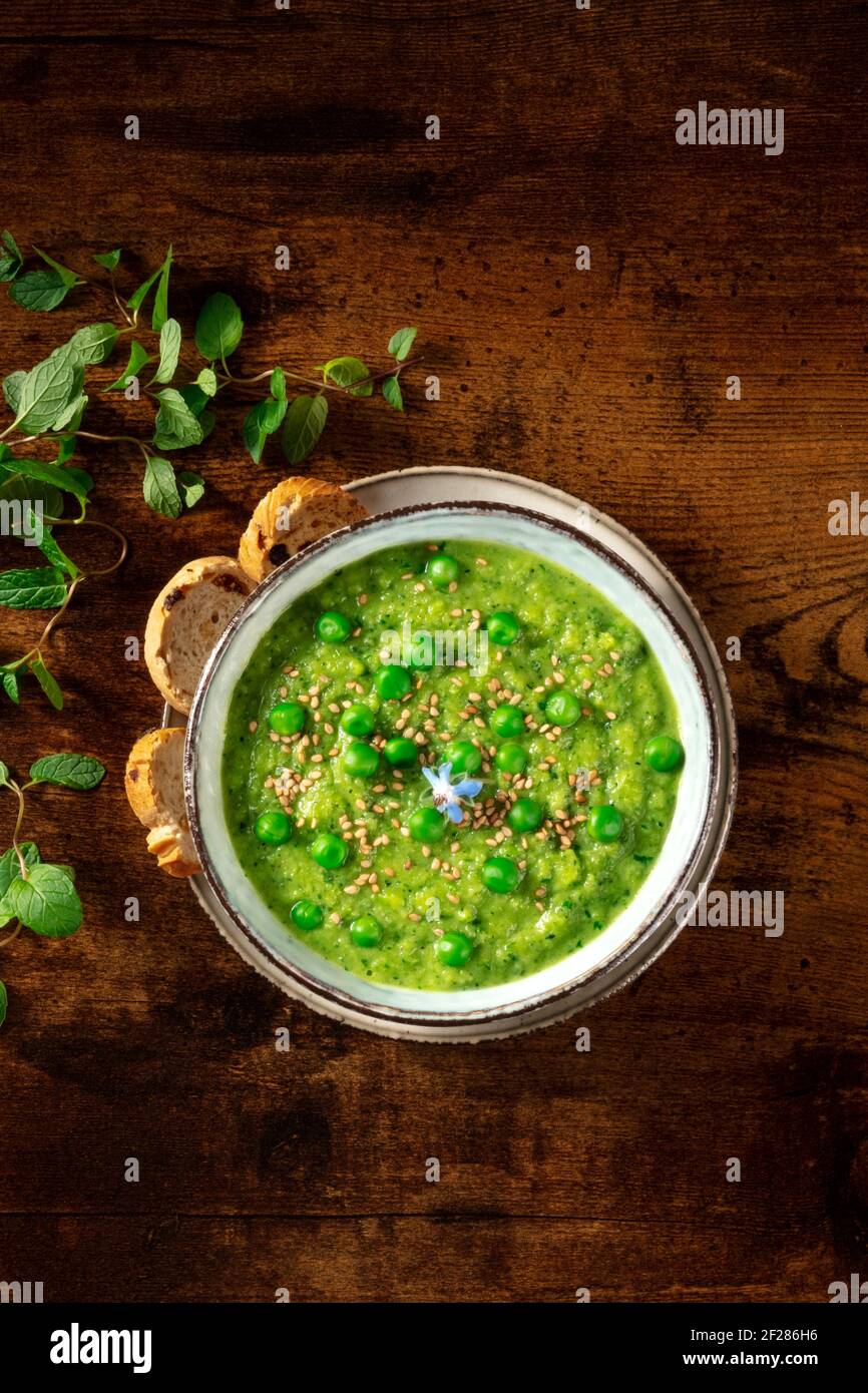 Zuppa vegana. Zuppa di crema verde, colpo d'asta su uno sfondo di legno rustico scuro Foto Stock