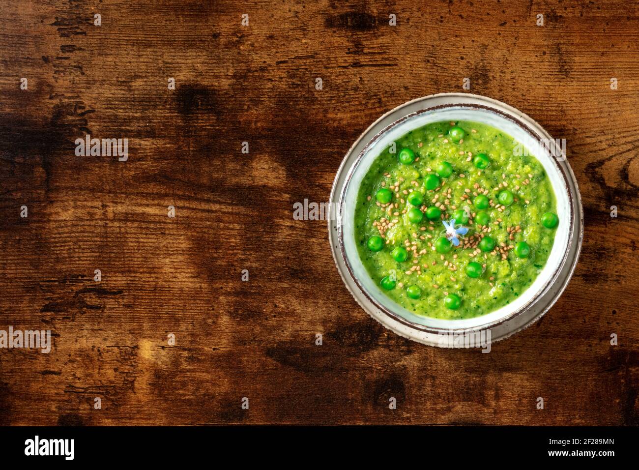 Zuppa verde vegana, colpo d'asta su uno sfondo di legno rustico scuro Foto Stock