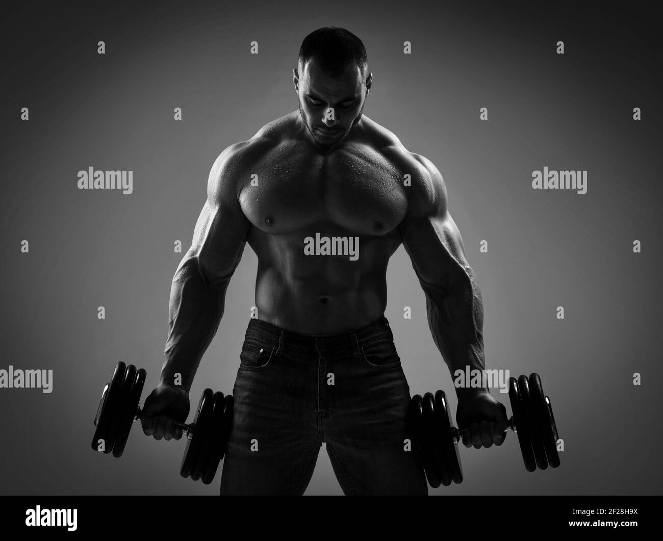 Gli uomini forti muscolari bodybuilder regge, sollevando grandi manubri pesanti in mani, sensazione di tensione nei muscoli Foto Stock
