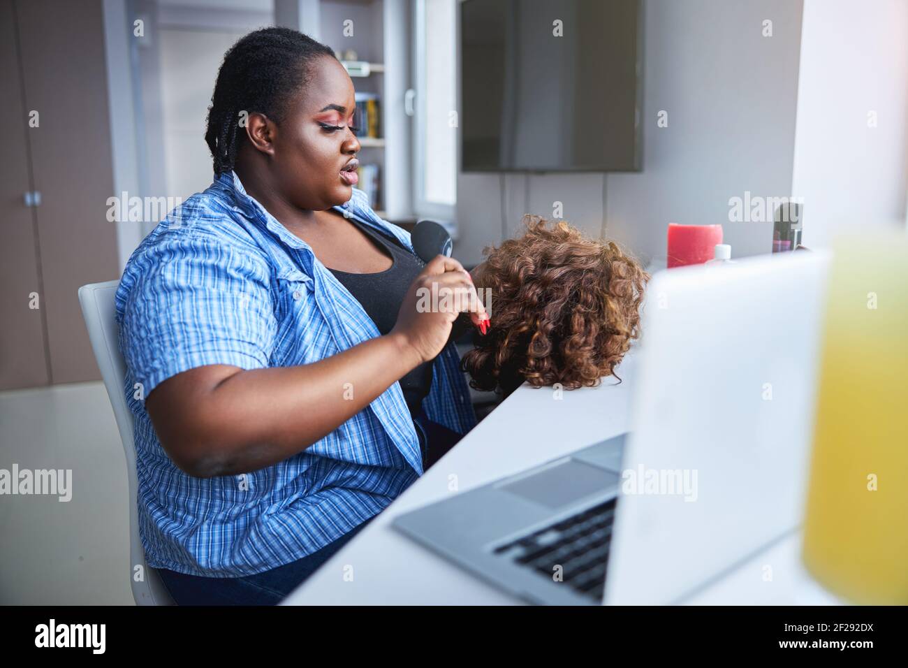 Bella donna afroamericana che fissa una parrucca riccia Foto Stock