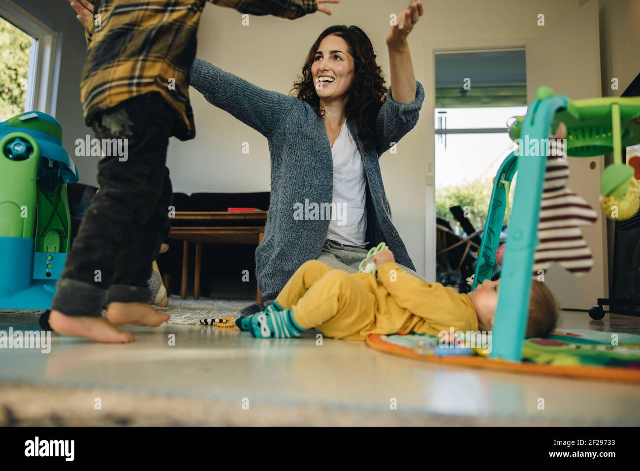 Madre che gioca con i suoi due bambini a casa. Donna in congedo di maternità trascorrendo del tempo con i suoi figli al chiuso. Foto Stock
