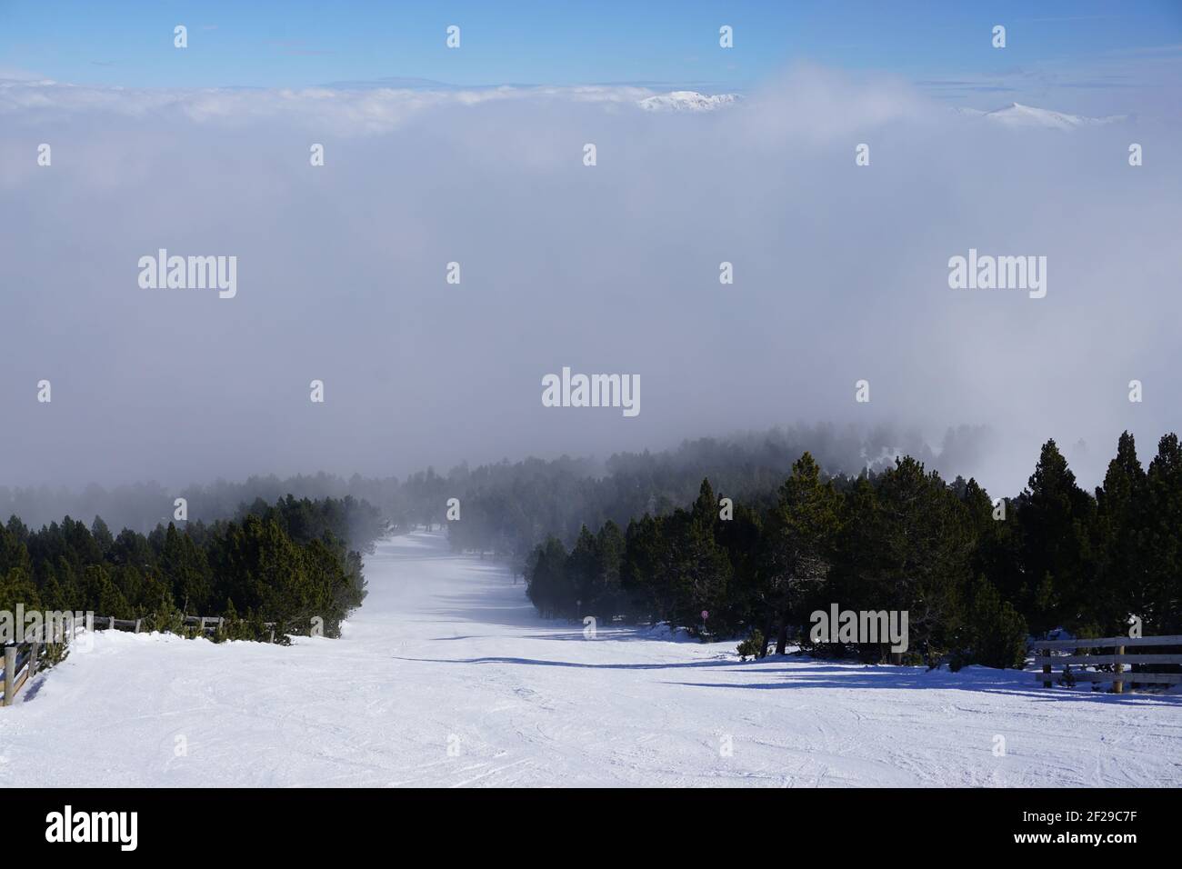 Pista da sci curata al sole sopra la nebbia nei Pirenei, Francia Foto Stock
