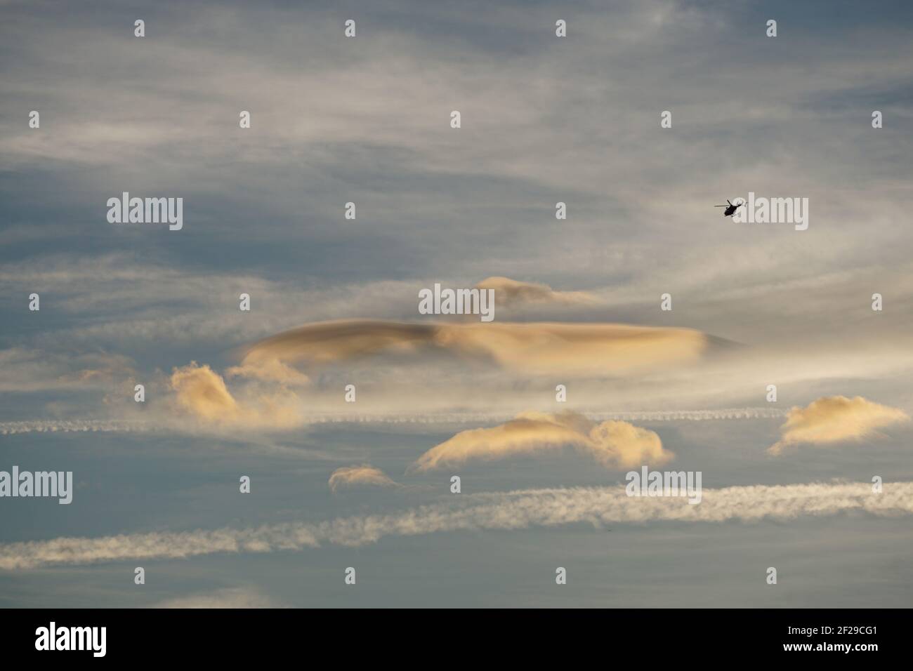 formazione di nubi funky al tramonto con un elicottero che vola intorno Foto Stock