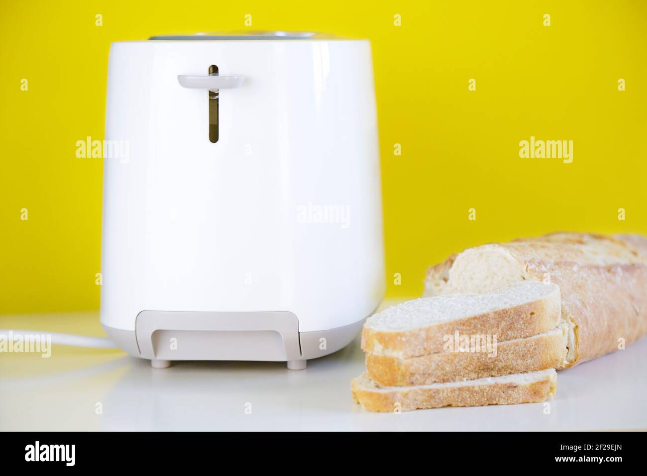 Tostapane e alcuni pezzi di pane francese contro il giallo sfondo Foto Stock