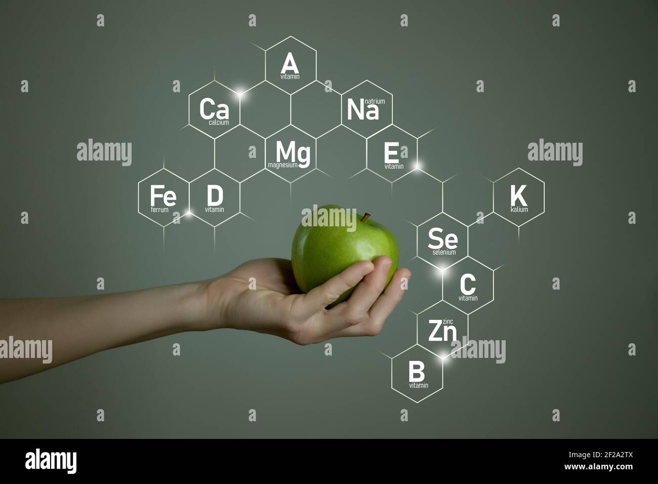 Donna`s mano che tiene la mela verde, icone microelementi in esagoni molecolari su sfondo grigio. Modello di concetto perdita di peso per la progettazione del prodotto. Foto Stock