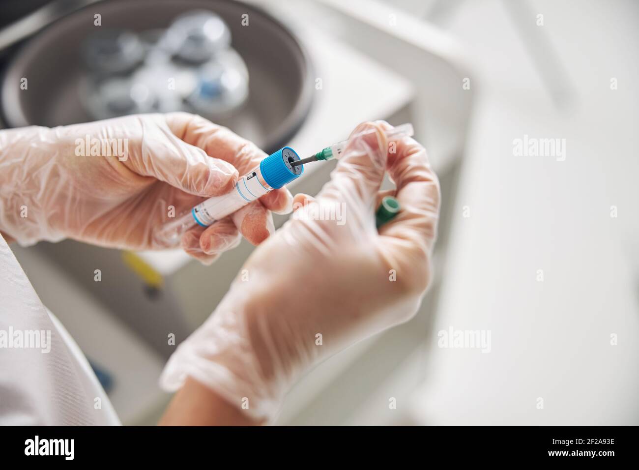 Le mani di un medico che tiene la provetta e l'ago Foto Stock