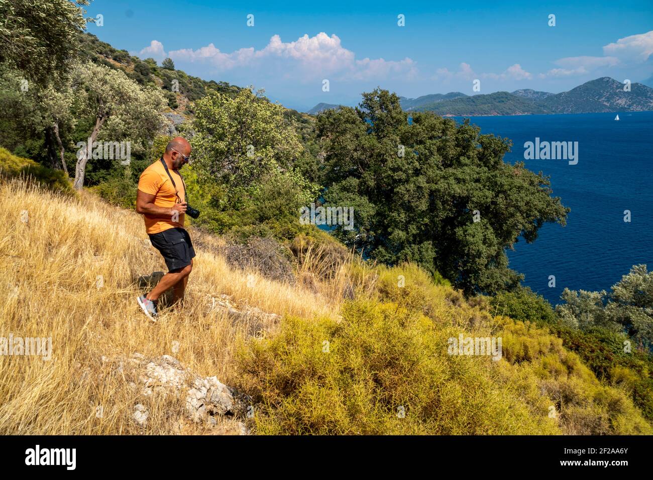 Un fotografo maschile caucasico casual sta scattando foto in natura. Sta tenendo una grande macchina fotografica nera. Il maschio adulto è all'aperto da solo e gratuito Foto Stock