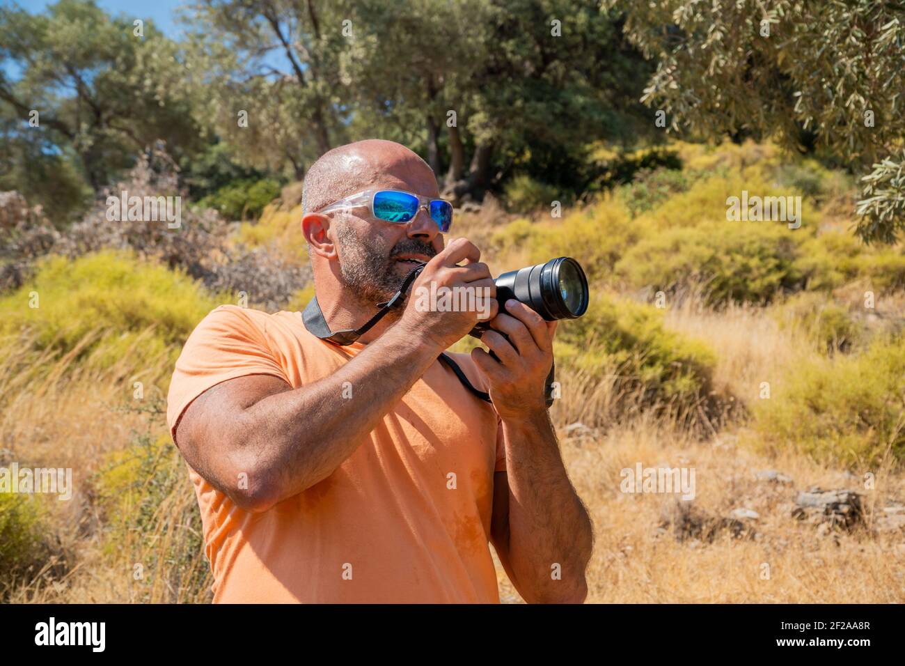 Un fotografo maschile caucasico casual sta scattando foto in natura. Sta tenendo una grande macchina fotografica nera. Il maschio adulto è all'aperto da solo e gratuito Foto Stock