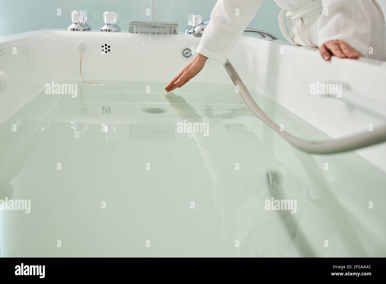 Le donne controllano l'acqua nella vasca da bagno prima della procedura di idromassaggio Foto Stock