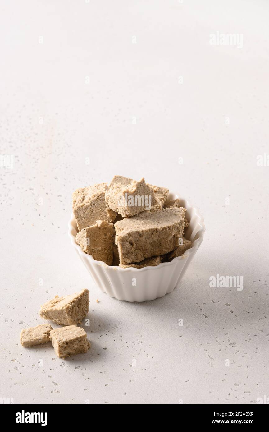 Halva dolce di girasole in ciotola bianca su sfondo bianco verticale. Primo piano. Foto Stock