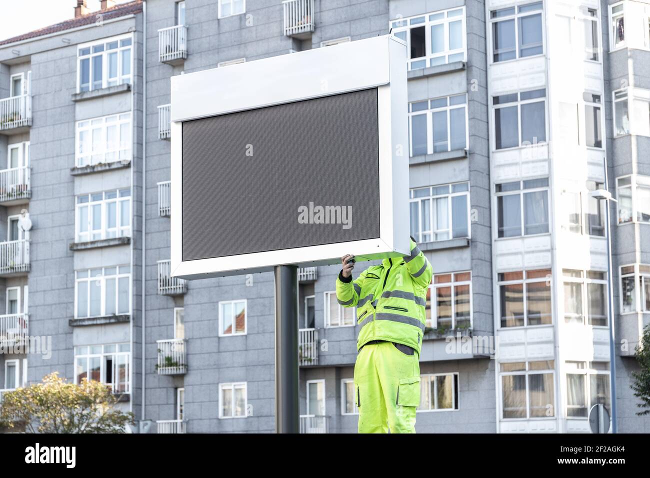 Lavoratore che installa un nuovo cartello elettronico sulla strada della città. Bock up Foto Stock