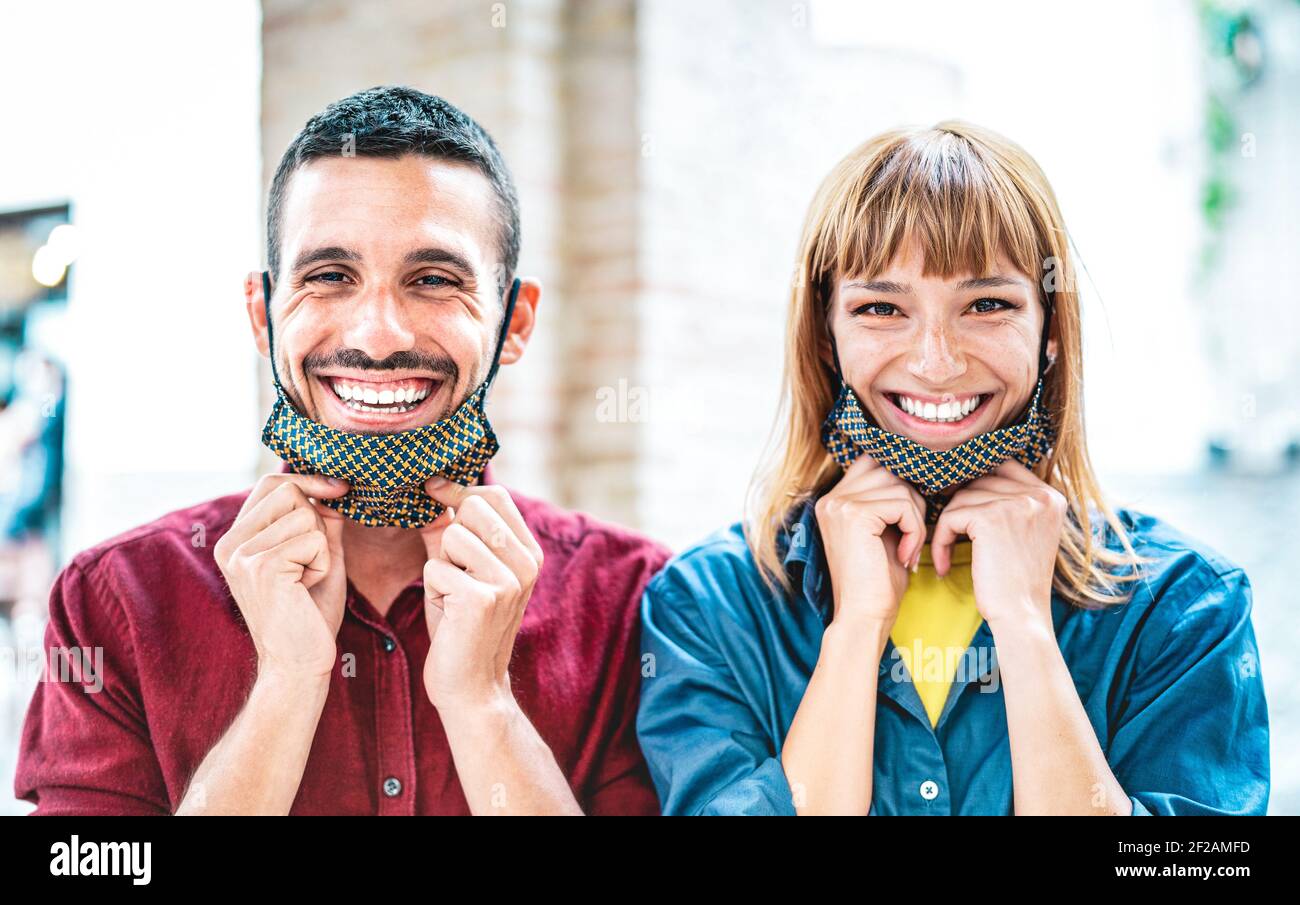Felice coppia innamorato sorridente con maschera aperta - Nuovo stile di vita normale e concetto di relazione con i giovani su umore positivo dopo il blocco Foto Stock