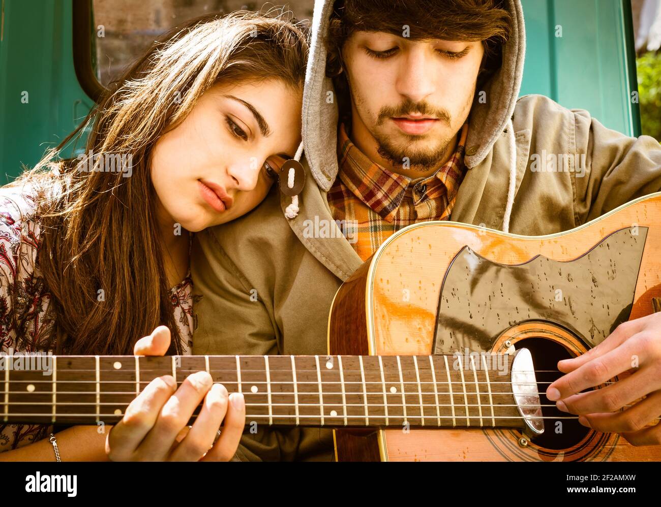 Giovane coppia romantica che suona la chitarra all'aperto dopo la pioggia Foto Stock