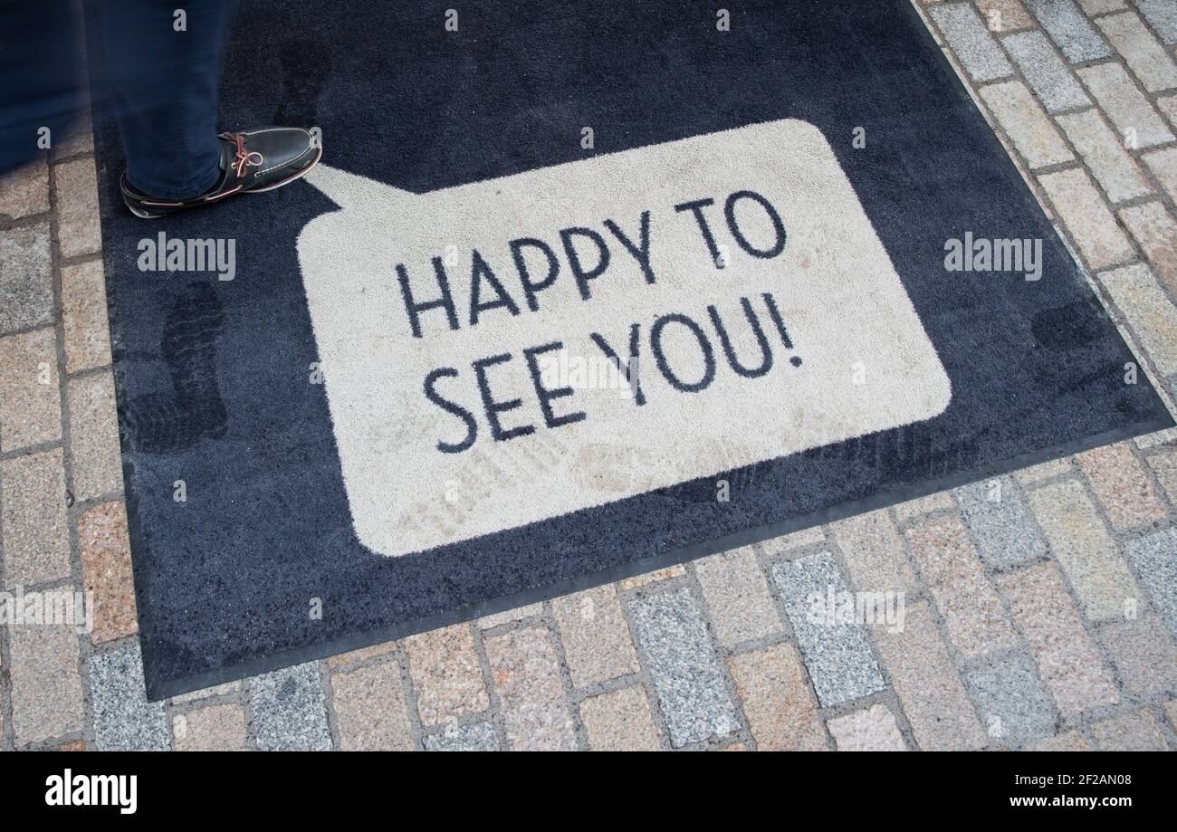 11 marzo 2021, Renania Settentrionale-Vestfalia, Bielefeld: 'Felice di vederti!' ('felice di vederti!') è scritto sul tappetino della porta di un negozio nella zona pedonale. Diversi comuni della NRW con bassi numeri di Corona stanno approfittando dell'allentamento locale del commercio e della cultura e offrendo i viaggi di shopping senza registrazione. Foto: Frito Gentsch/dpa Foto Stock