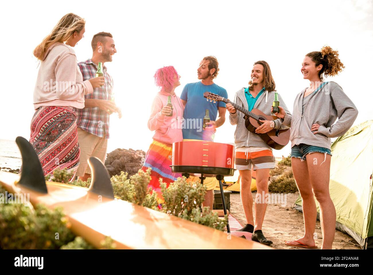 Amici hipster divertirsi in spiaggia campeggio festa - Wanderlust concetto di viaggio con i giovani viaggiatori tostare e bere in bottiglia birra insieme Foto Stock