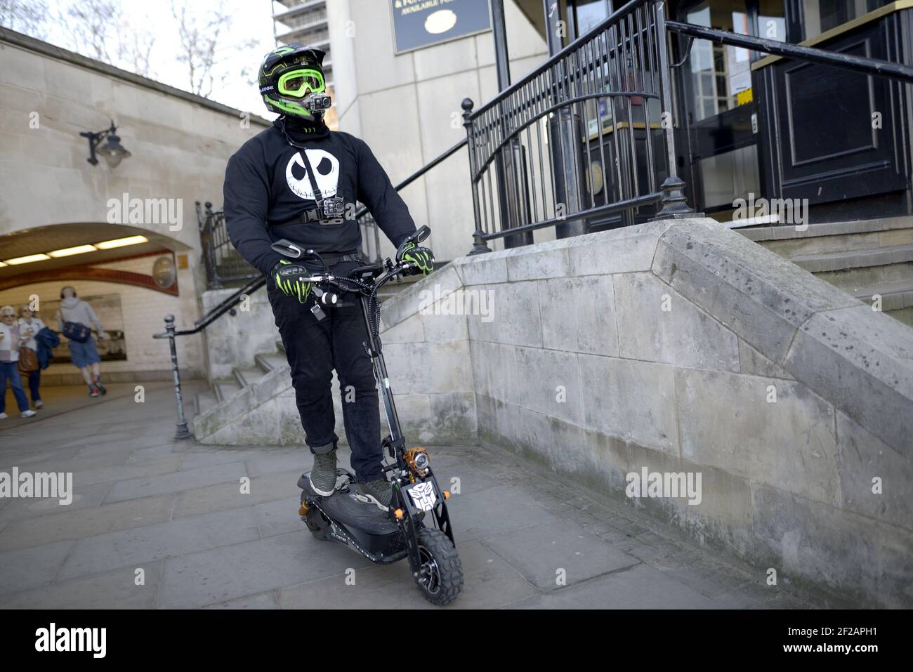 Londra, Inghilterra, Regno Unito. Uomo in un casco che indossa due Bodycams che guidano un e-scooter SXT Moster sul marciapiede, South Bank Foto Stock