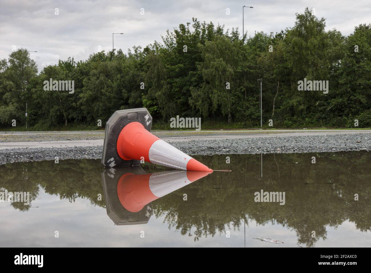 Road Cone rovesciato - riflessione nel Puddle, cono di traffico rovesciato in puddle di acqua Foto Stock