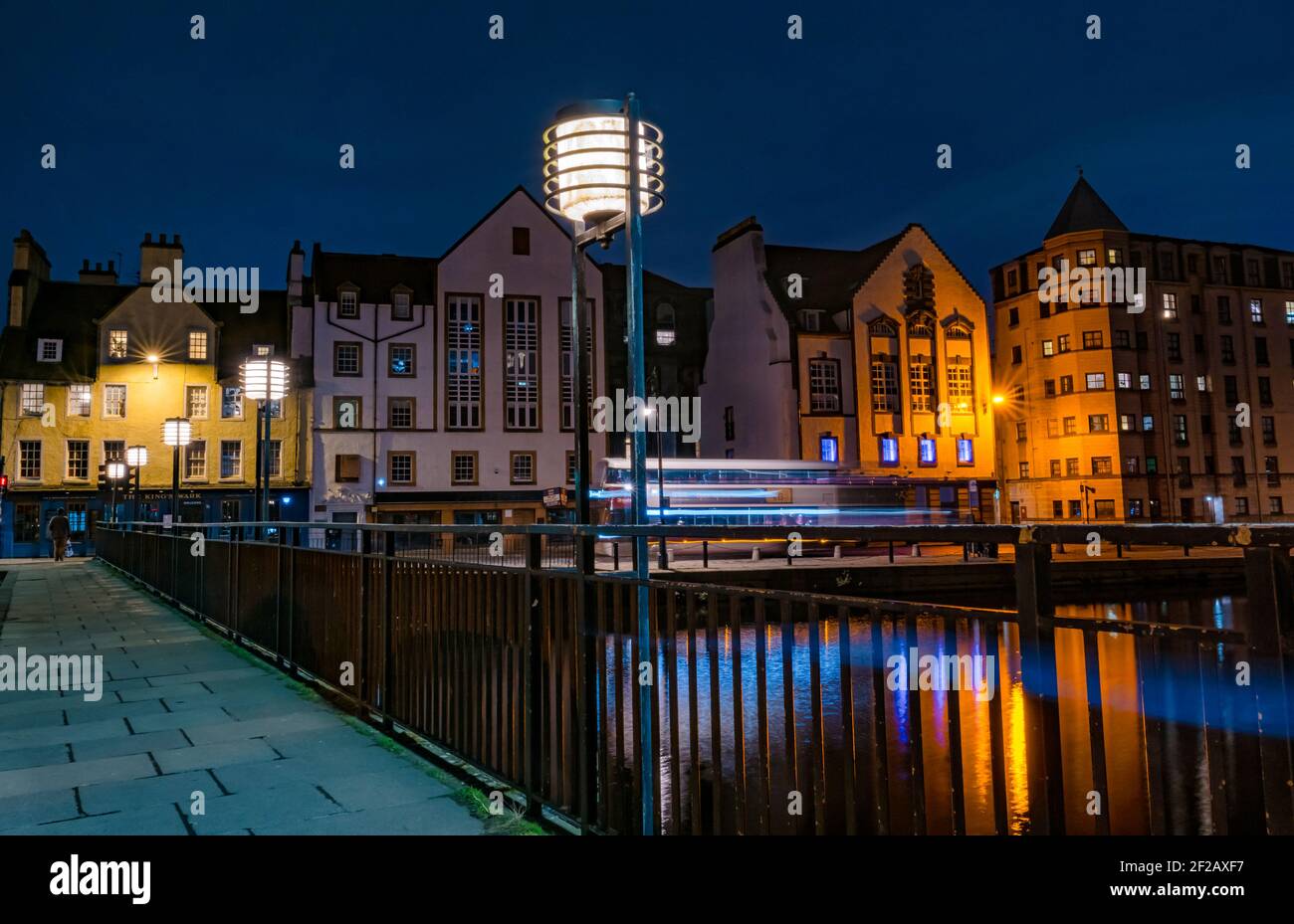 Il ponte in stile Art Deco si illumina di notte e gli edifici storici sulle acque della riva del fiume Leith, della Shore, di Leith, di Edimburgo, Scozia, REGNO UNITO Foto Stock