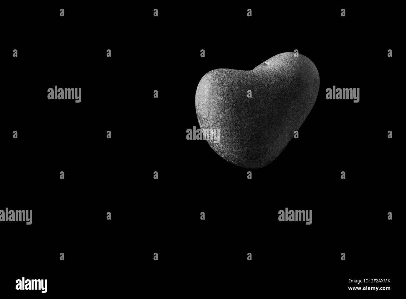 Una pietra a forma di cuore nell'aria, nera, nera e bianca, a forma di cuore, cuore di roccia, L'amore è nell'aria, il cuore di ciottoli, giorno di valentine, 14 ° Fe Foto Stock