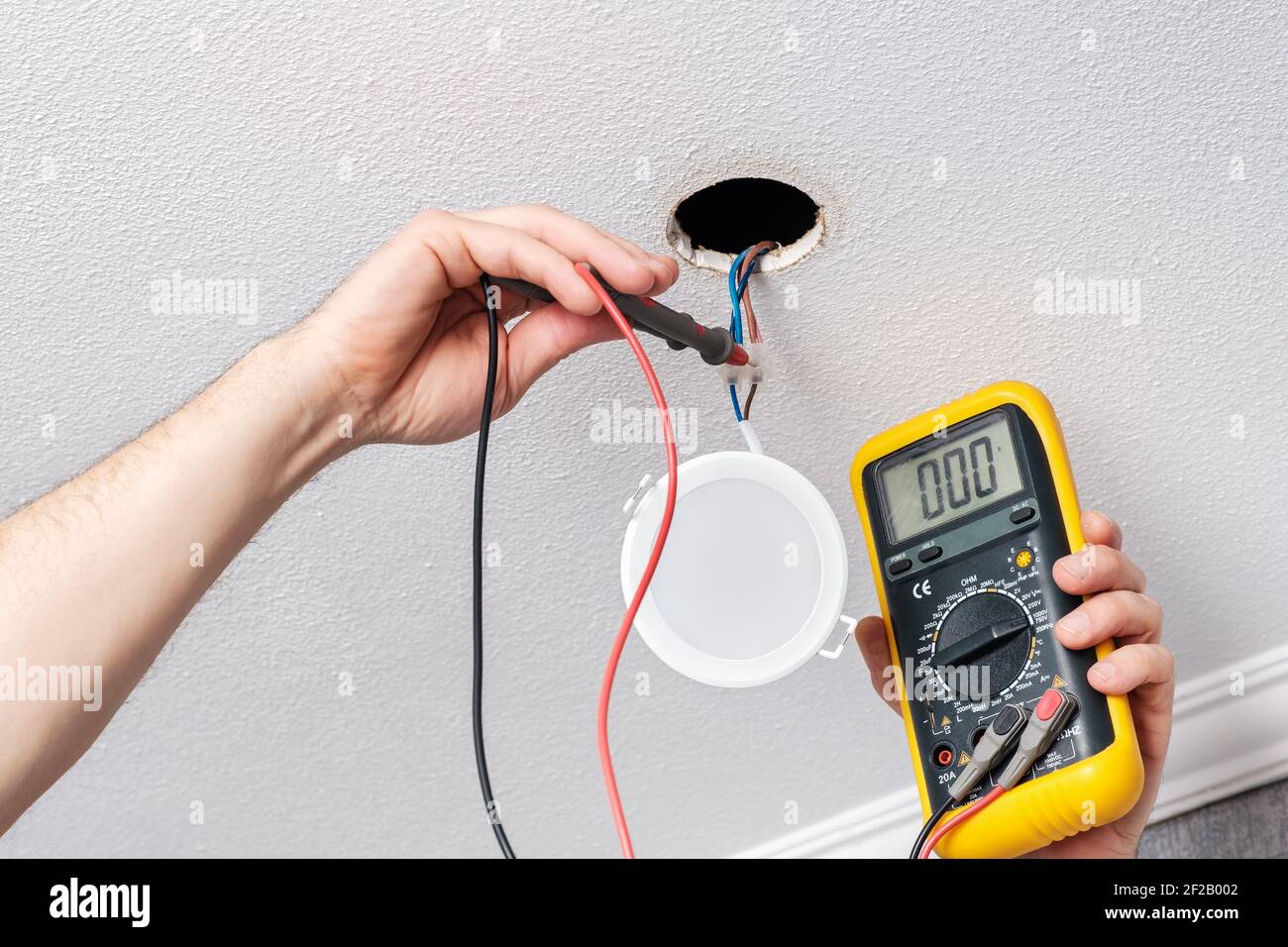 Prima di installare il LED, controllare le mani dell'elettricista con  l'alimentazione del tester leggero Foto stock - Alamy