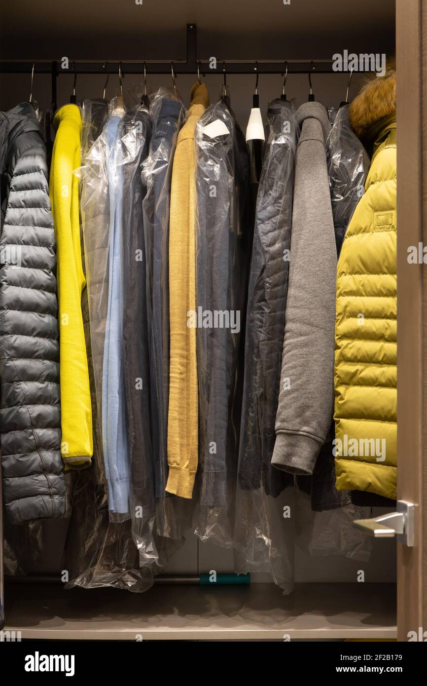 Un piccolo spogliatoio nell'appartamento dell'uomo. Gli abiti da uomo alla moda in colori neutri pendono saldamente sulle appendiabiti. Concetto di moda, appartamento, casa d Foto Stock
